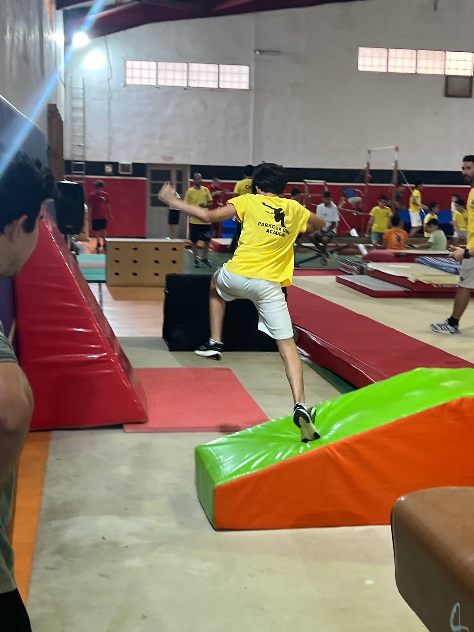 Saut et franchissement par un adhérent en maillot jaune Parkour Oran Academy