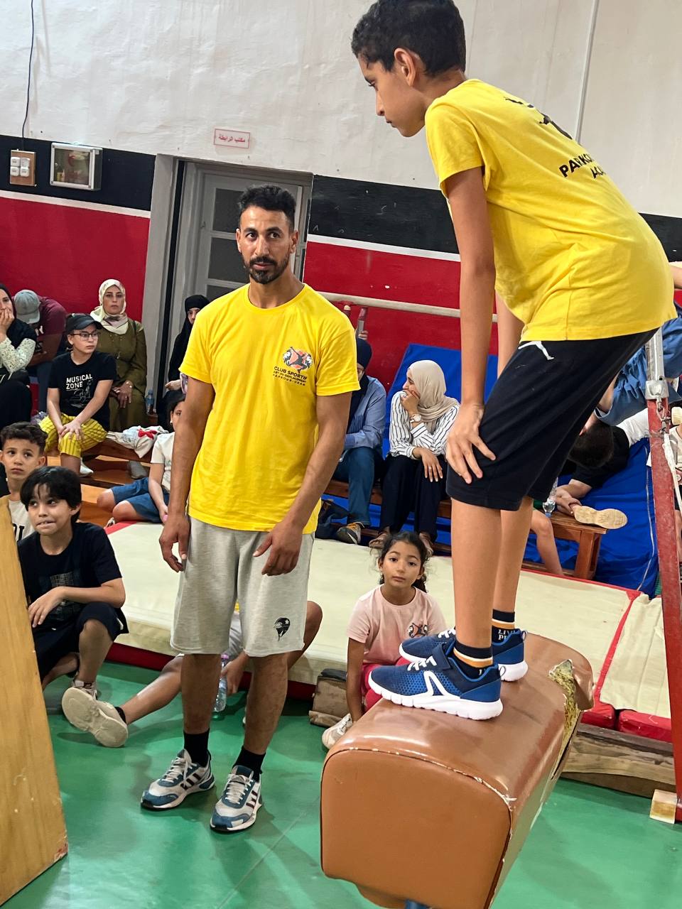 Coach principal guidant un élève devant les spectateurs